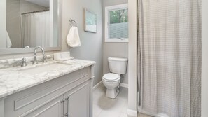Ein Badezimmer mit Marmorwaschbecken, Toilette und Duschvorhang.