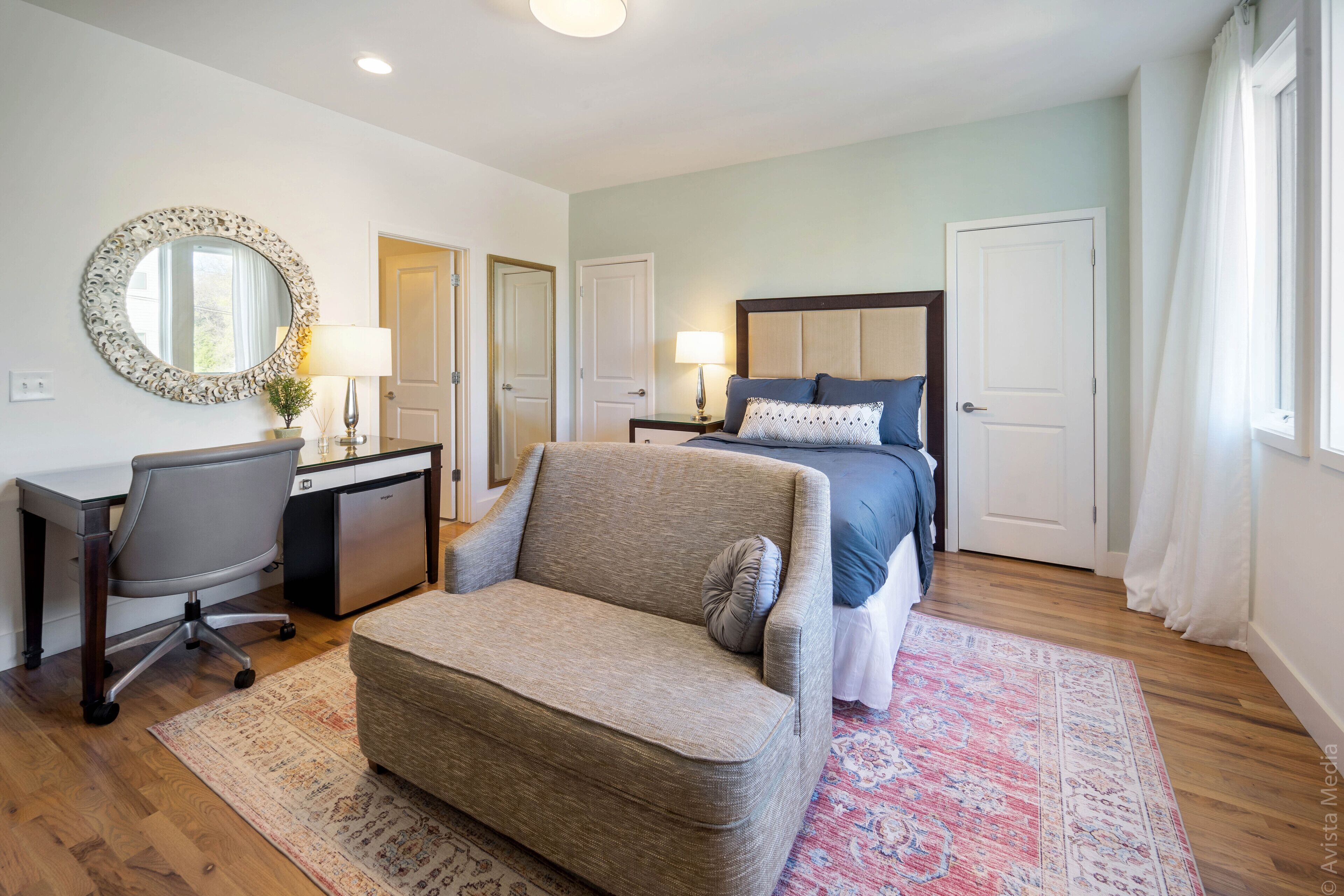 A bedroom with a bed, a sofa, a desk, and a chair.