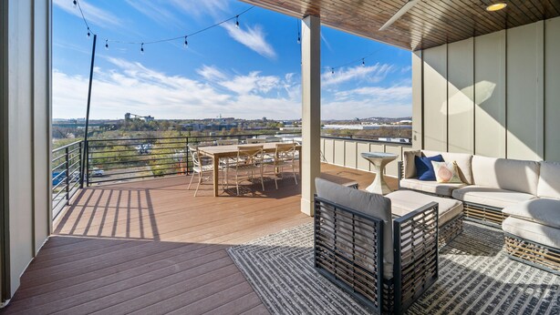 Een balkon met een houten terras, buitenmeubilair en uitzicht op de stad.
