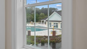 A view through a window of a pool area with a building in the background. - Villa #706: 4  BR, 3  BA Condominium in Garden City, Sleeps 8 (Garden City)