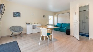 A modern living room with a dining area, a sofa, a TV, and a shower room.