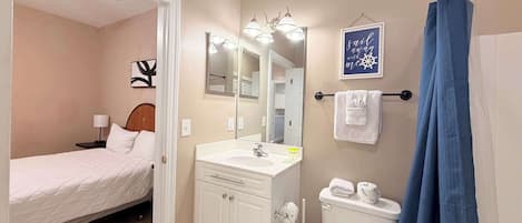 A hotel room with a bed, a bathroom with a sink, mirror, and a towel rack.