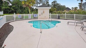 Une piscine dotée d’un poste de surveillance pour les sauveteurs, entourée d’une clôture blanche, et un petit bâtiment portant le numéro 4503.