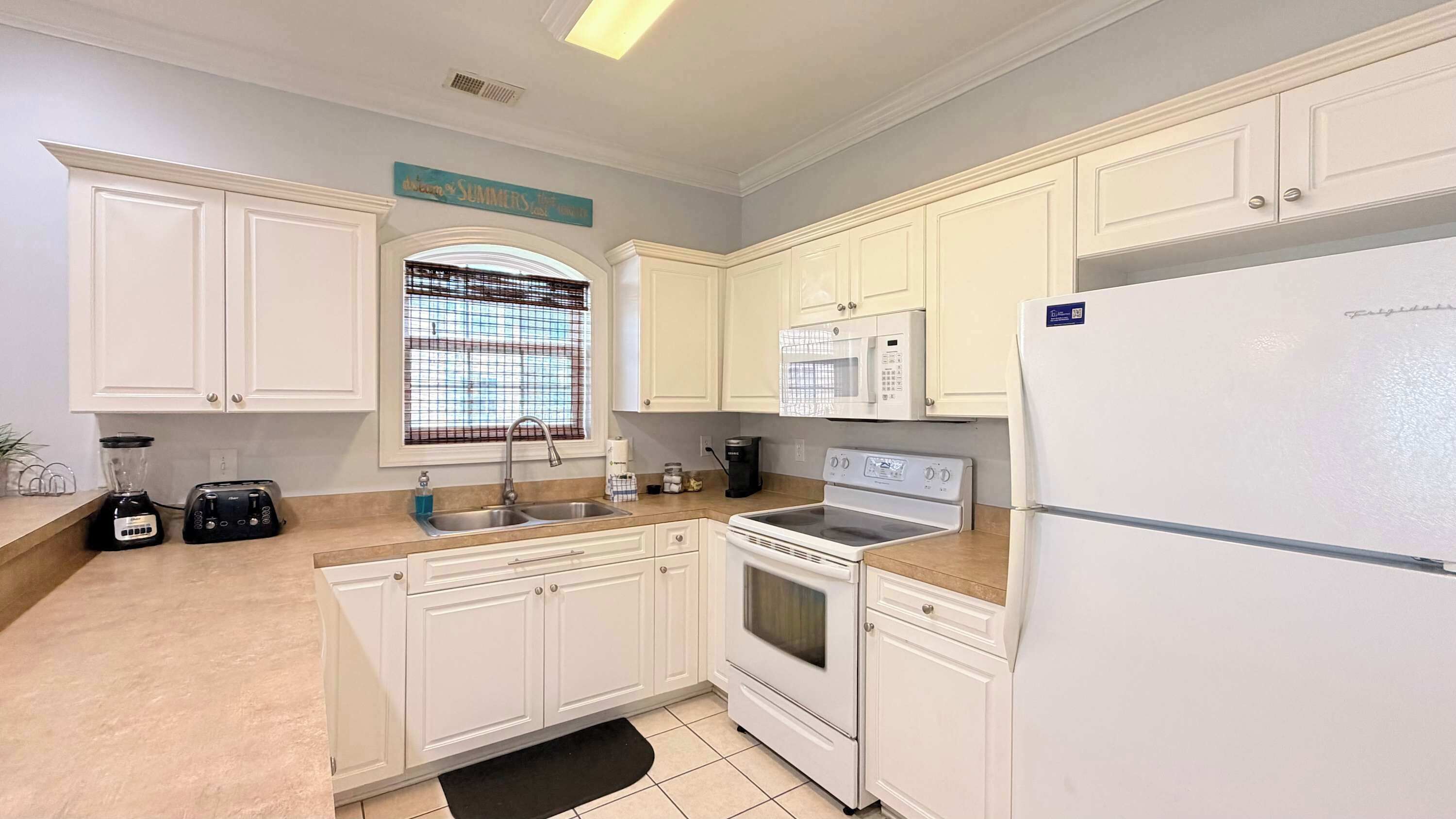A kitchen with white cabinets, a microwave, a refrigerator, a stove, and a sink.