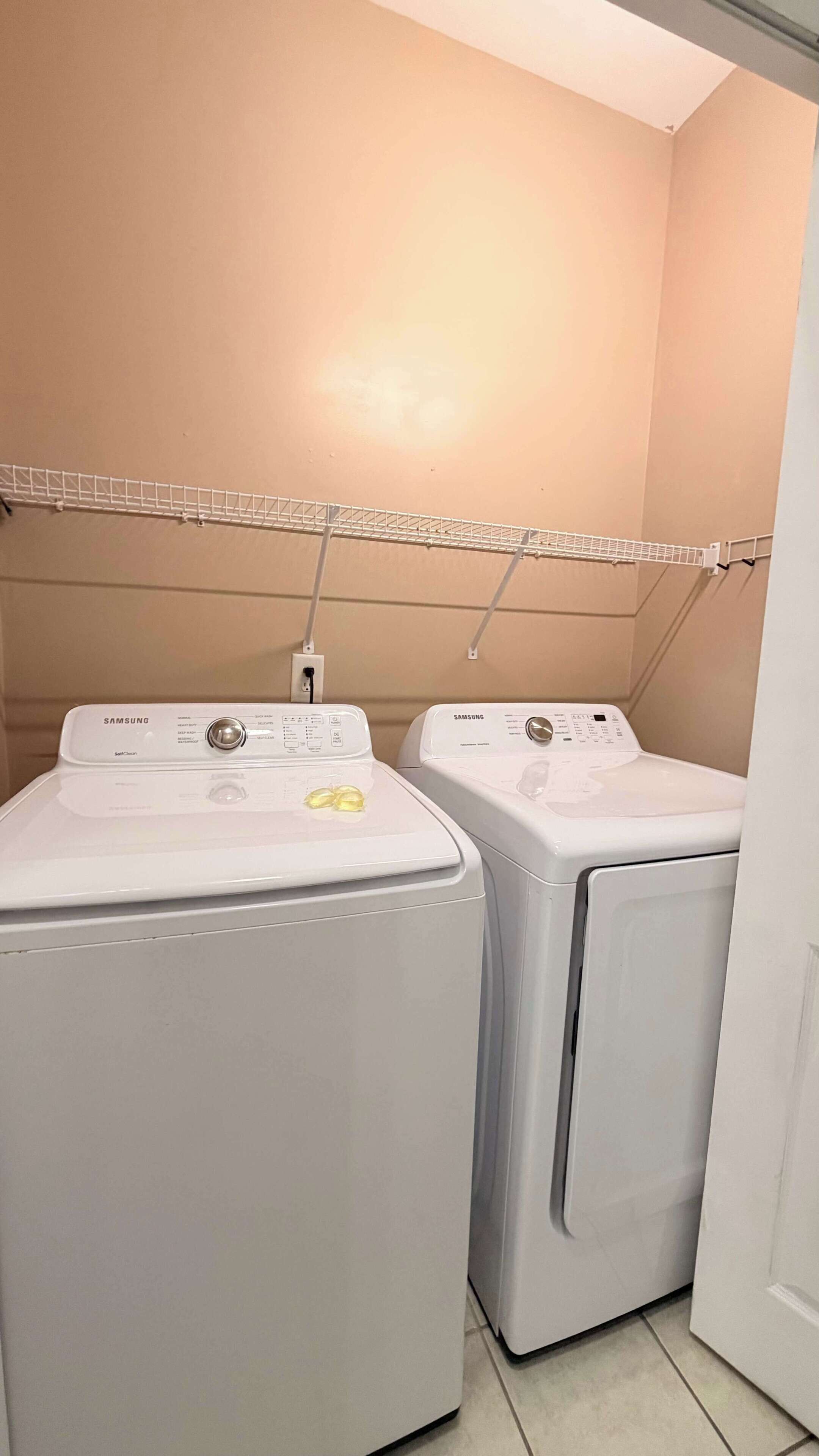 Un espace buanderie équipé de deux lave-linge Samsung à chargement frontal, de couleur blanche, et d’un étendoir placé au-dessus.