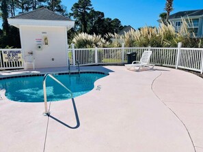 A swimming pool with a no lifeguard sign, a white fence, and a small building with the number 4803.
