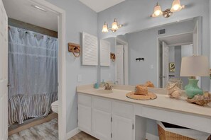 A bathroom with a double sink, a shower, and a vanity with a mirror.