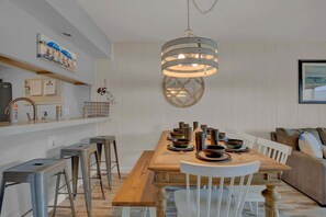 A dining area with a wooden table set for four, surrounded by white chairs. A modern pendant light hangs above the table. - A Fishers ParadiseW/Boatdock! (Rockport)