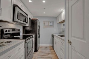 A modern kitchen with stainless steel appliances, white cabinetry, and a tiled backsplash. - A Fishers ParadiseW/Boatdock! (Rockport)