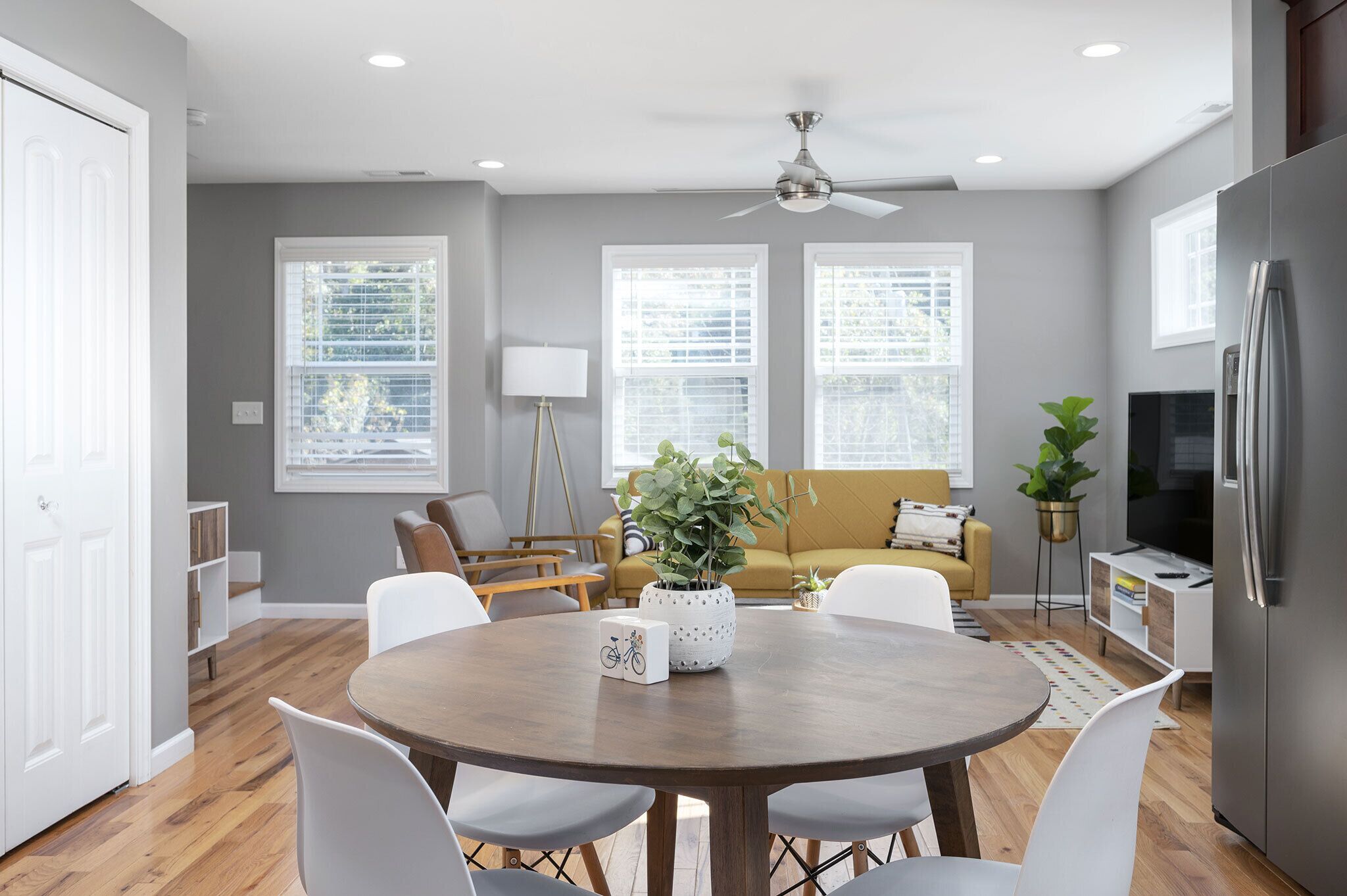 A modern kitchen with a dining area, a sofa, and a TV.