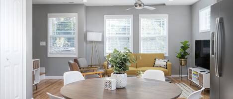 A modern kitchen with a dining area, a sofa, and a TV.
