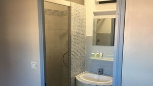A bathroom with a shower, a sink, and a mirror. - T2 APARTMENT IN THE CENTER OF TOWN, 5 MINUTES FROM THE SPA (Balaruc-les-Bains)