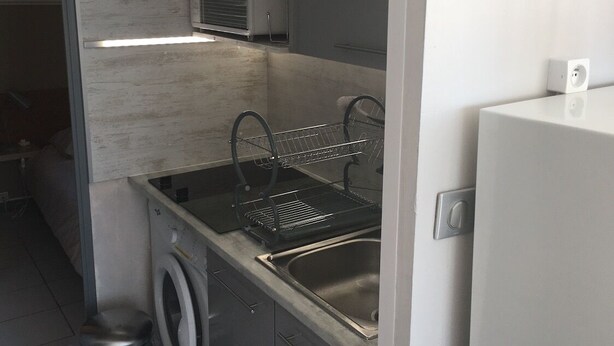 A compact kitchen with a washing machine, a dishwasher, and a built-in oven. - T2 APARTMENT IN THE CENTER OF TOWN, 5 MINUTES FROM THE SPA (Balaruc-les-Bains)