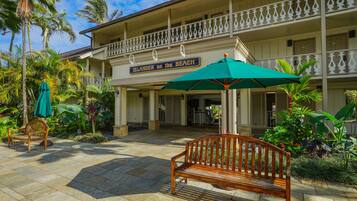 A hotel with a balcony, a wooden bench, and a sign that reads "Islander on the Beach".