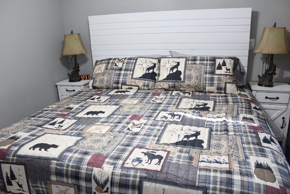 A bed with a quilt featuring animal prints and a white headboard. - Lake View cottage, secluded, quiet, total remodel, 3 king beds (Wagoner)