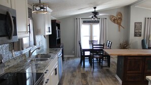 Una cocina con encimeras de granito, electrodomésticos de acero inoxidable y un comedor con mesa y sillas de madera.