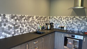 Een moderne keuken met een backsplash van hexagontegels, een inbouwoven en een roestvrijstalen afzuigkap.