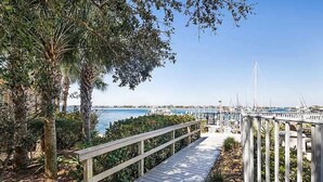 A wooden boardwalk leading to a marina with boats and a clear blue sky.