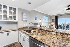A kitchen with granite countertops, white cabinetry, and a built-in dishwasher.