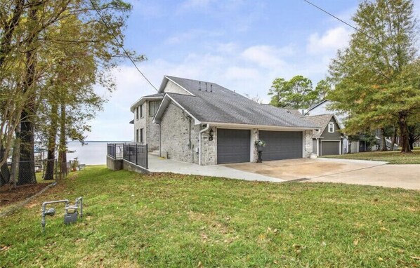 Une maison à deux étages avec un garage, une allée couverte et une vue sur l’eau.