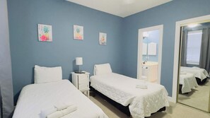 A hotel room with two beds, a nightstand, a mirror, and a door leading to a bathroom. - Pond view beautiful apartment at Magnolia Place (Myrtle Beach)