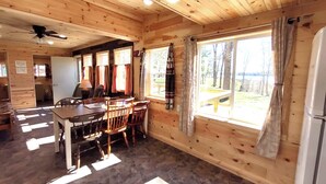 L’intérieur d’un chalet en bois comprend un coin repas, un sol en pierre et offre une vue sur l’extérieur.