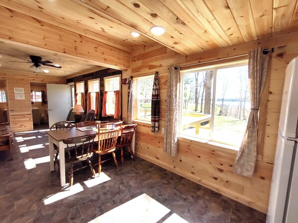 L’intérieur d’un chalet en bois comprend un coin repas, un sol en pierre et offre une vue sur l’extérieur.