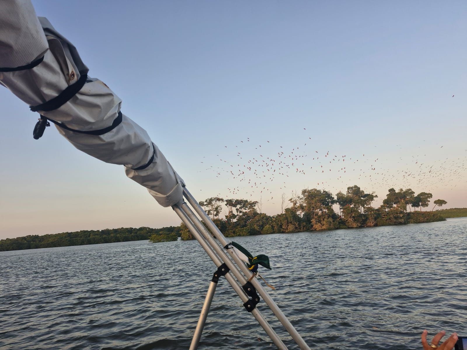 A telescope on a boat with a lake and trees in the background.