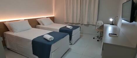 A hotel room with two beds, a desk with a computer, and a TV.