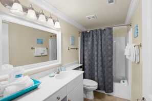 A bathroom with a white sink, large mirror, and a shower with a patterned curtain.