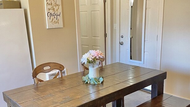A dining table with benches, a vase with flowers, and a motivational quote on the wall. - Entire Studio Apartment - close to town BRAND NEW AC (Missoula)