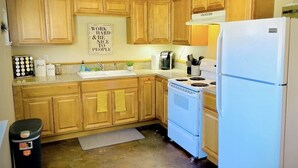 A kitchen with wooden cabinets, a white refrigerator, a stove, and a coffee maker. - Entire Studio Apartment - close to town BRAND NEW AC (Missoula)