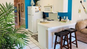 A compact kitchen with white cabinets, a central island, and a blue accent wall. - Simply beautiful 1 floor condo in the center of MB (Myrtle Beach)