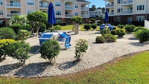 A residential building with multiple balconies, a swimming pool, and a landscaped garden area. - Simply beautiful 1 floor condo in the center of MB (Myrtle Beach)