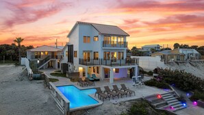 A two-story house with a swimming pool, outdoor seating, and a balcony. - Pool, 7 Bed 7 Bath, Direct Oceanfront, 4 Kitchens (Port Orange)
