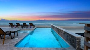 A swimming pool with lounge chairs and a view of the ocean at sunset. - Pool, 7 Bed 7 Bath, Direct Oceanfront, 4 Kitchens (Port Orange)
