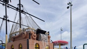 Een waterpark in piratenthema met een schipconstructie, glijbanen en een brug van netten.
