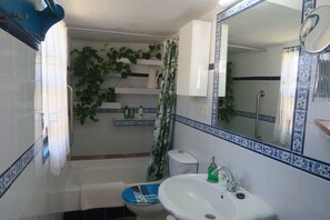 A bathroom with a white sink, a blue basin, a white toilet, and a shower curtain.