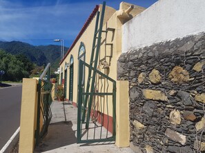 Un bâtiment à la façade jaune, doté d’un portail vert et d’un mur en pierre.