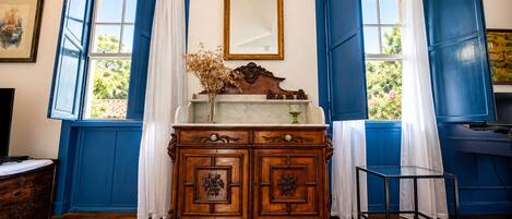 A room with a wooden cabinet, a mirror, and blue shutters on the windows.