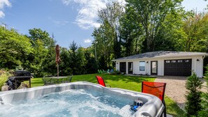 Un jacuzzi en un patio trasero con una casa pequeña y un garaje.