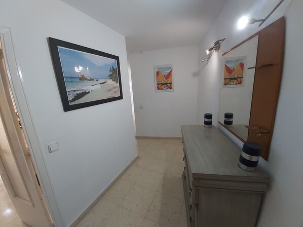 A hallway with a framed beach photo, a mirror, and a small table with two containers. - Stunning views from spacious 2 bedroom apartment (L'Alfàs del Pi)