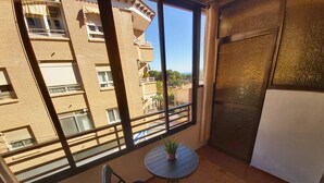 Un balcone con vista su un edificio in mattoni, un tavolino rotondo, due sedie e una pianta in vaso.