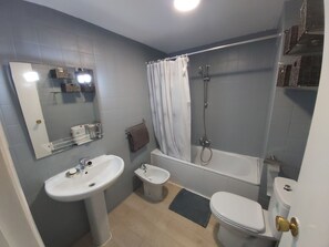 Een bad/douchecombinatie, een haardroger, een bidet, handdoeken