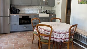 A compact kitchen with grey cabinets, a built-in oven, and a dining table with four chairs. - Modern apartment 10min to walk to the city center WITH swimming pool (Cotignac)