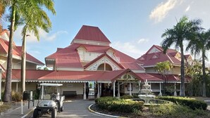 A hotel with a red-roofed building, a covered entrance, and a fountain. - Studio 4 pers vue mer et cocotiers Village Vacances Ste-Anne, Pointe du Helleux (Sainte Anne)