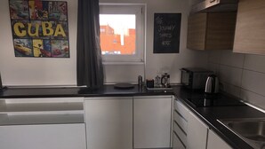 A modern kitchen with white cabinets, a black countertop, a coffee maker, and a chalkboard with 'THE JOURNEY STARTS HERE'. - KW38 - 2 min to Old Market Square and Townhall (Wroclaw)