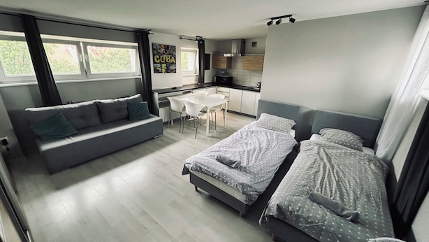 A compact bedroom with a sofa, two single beds, a small table, and a kitchenette. - KW38 - 2 min to Old Market Square and Townhall (Wroclaw)