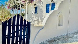 A white building with blue shutters and a wooden gate. - Villa Arietta Santorini (Santorini)
