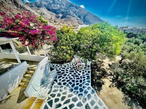 A staircase leading to a terrace with a mountain view, surrounded by lush greenery and flowering plants. - Villa Arietta Santorini (Santorini)